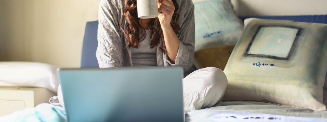 Woman using laptop and holding coffee mug