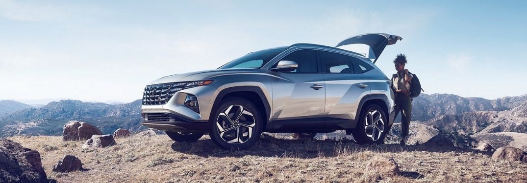 Silver 2022 Hyundai Tucson on a Hill with Woman Putting Cargo in the Back