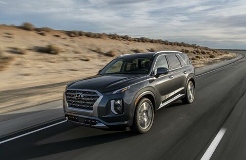 Hyundai Palisade SUV driving on a desert road.