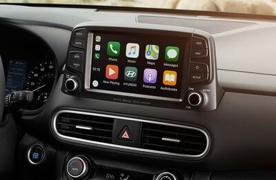 A close-up of the dashboard of a Hyundai Kona, showcasing the touchscreen display with various Apple CarPlay icons.