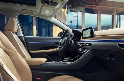 Dashboard and front seats of a Hyundai Sonata, with a focus on the steering wheel and infotainment screen, showcasing the interior design. 