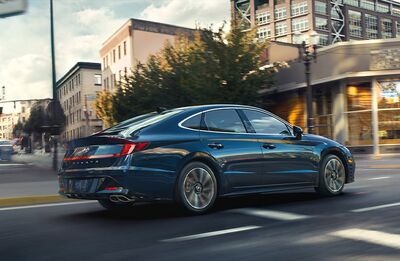 Blue Hyundai Sonata driving on a city street.