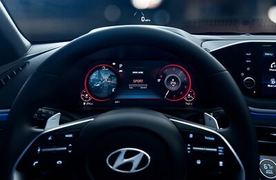 Interior view of a Hyundai Sonata, showing the steering wheel, digital instrument cluster, and infotainment screen. 