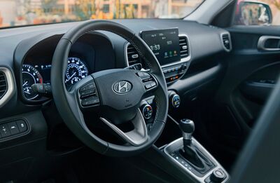 A red Hyundai Venue parked in front of a graffiti-covered brick wall.