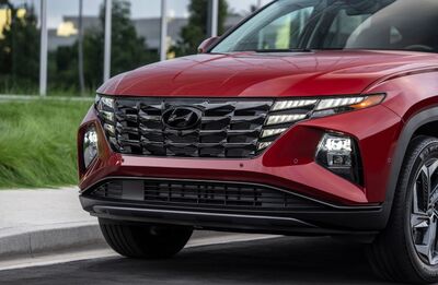 A close-up of the front of a red Hyundai Tucson, showcasing its distinctive grille and headlights.