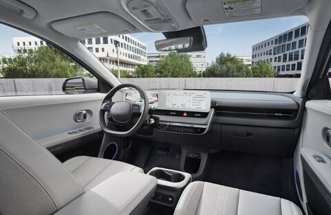 The interior of a Hyundai Ioniq 5, showcasing a minimalist design with a large, curved touchscreen display spanning the width of the dashboard.