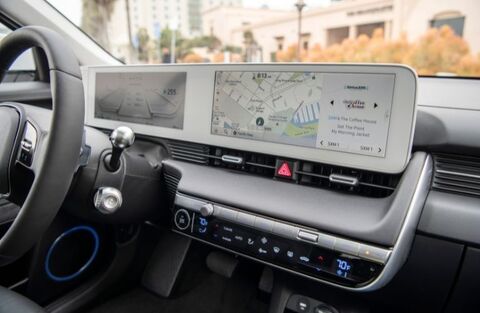 A close-up of the Hyundai Ioniq 5's dashboard, featuring a wide, curved display with a navigation map visible.