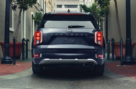 A rear view of a dark blue Hyundai Palisade parked on a city street.