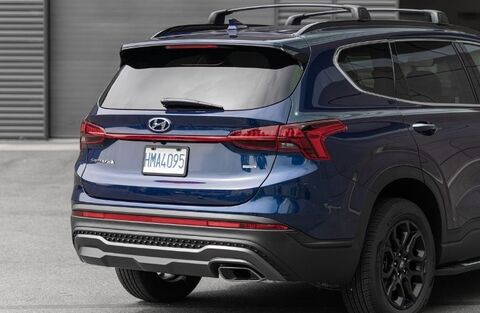 A rear view of a dark blue Hyundai Santa Fe with a roof rack.