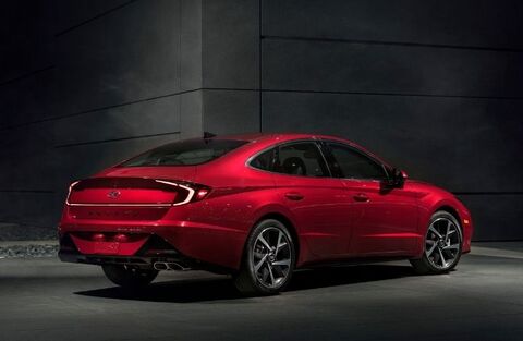 A rear three-quarter view of a red Hyundai Sonata parked in front of a dark wall. The car's sleek lines and distinctive taillights are highlighted.