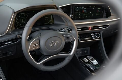 The interior of a Hyundai Sonata, showcasing the driver's perspective. The image highlights the steering wheel, dashboard with a digital instrument cluster and infotainment screen, and various controls.