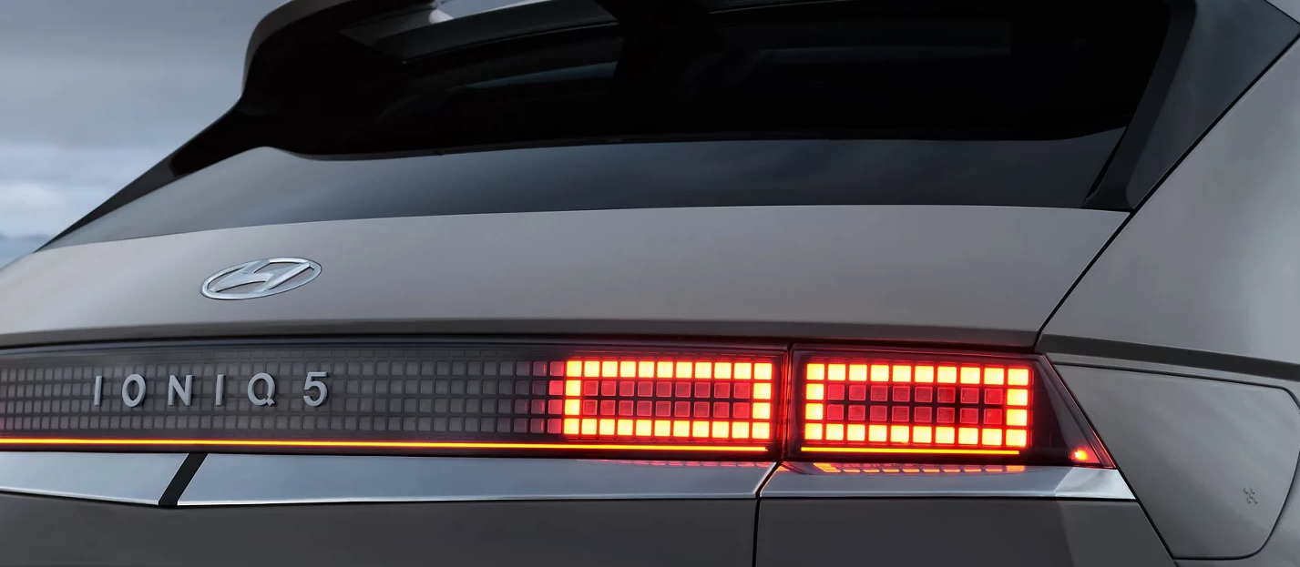 A close-up of the rear of a Hyundai Ioniq 5, highlighting the distinctive pixelated taillights and the illuminated "IONIQ 5" lettering.