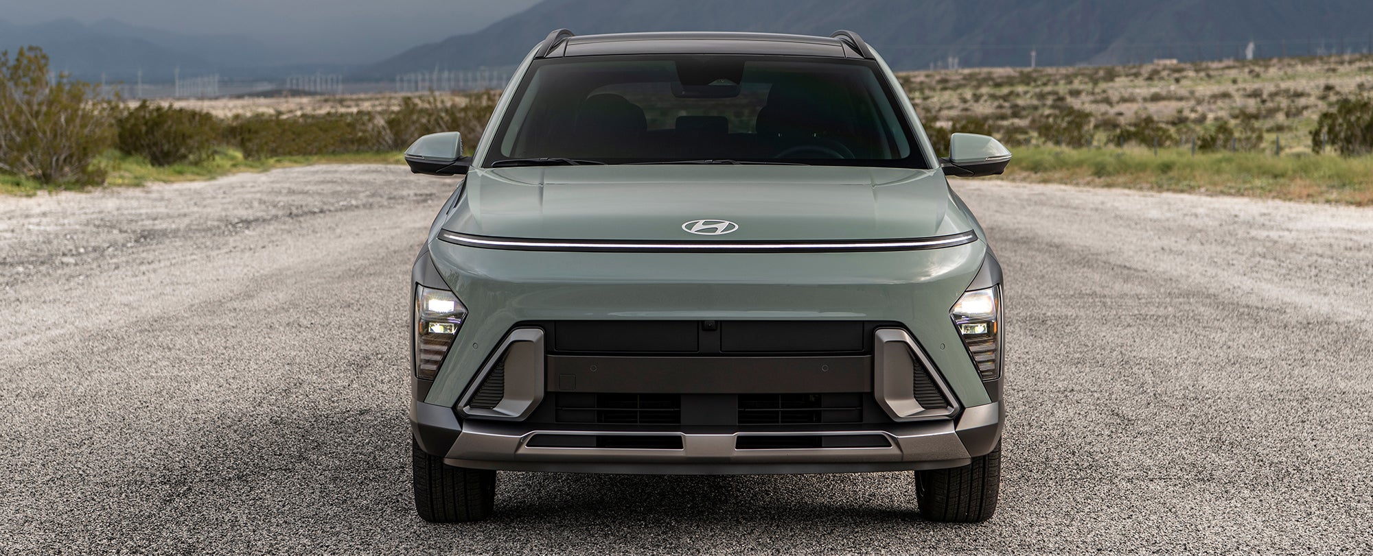 A front view of a gray Hyundai Ioniq 5 parked on a desert road with mountains in the background.