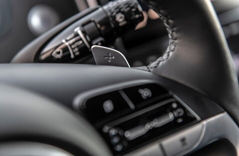 A close-up of the steering wheel and shift paddles in a Hyundai vehicle. The steering wheel is wrapped in leather and features controls for various functions.