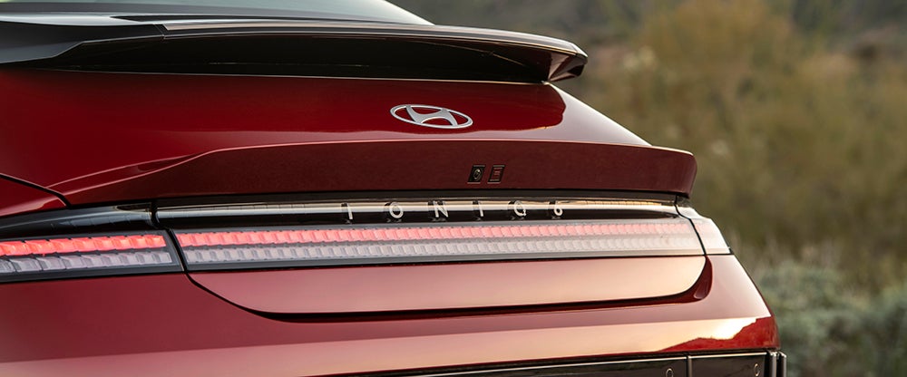A close-up of the rear of a red Hyundai IONIQ 6, showing its pixelated taillights and spoiler.