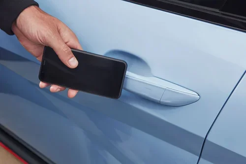 A service technician in a Hyundai uniform and gloves uses a pneumatic impact wrench to tighten the lug nuts on a car's wheel in a service bay.