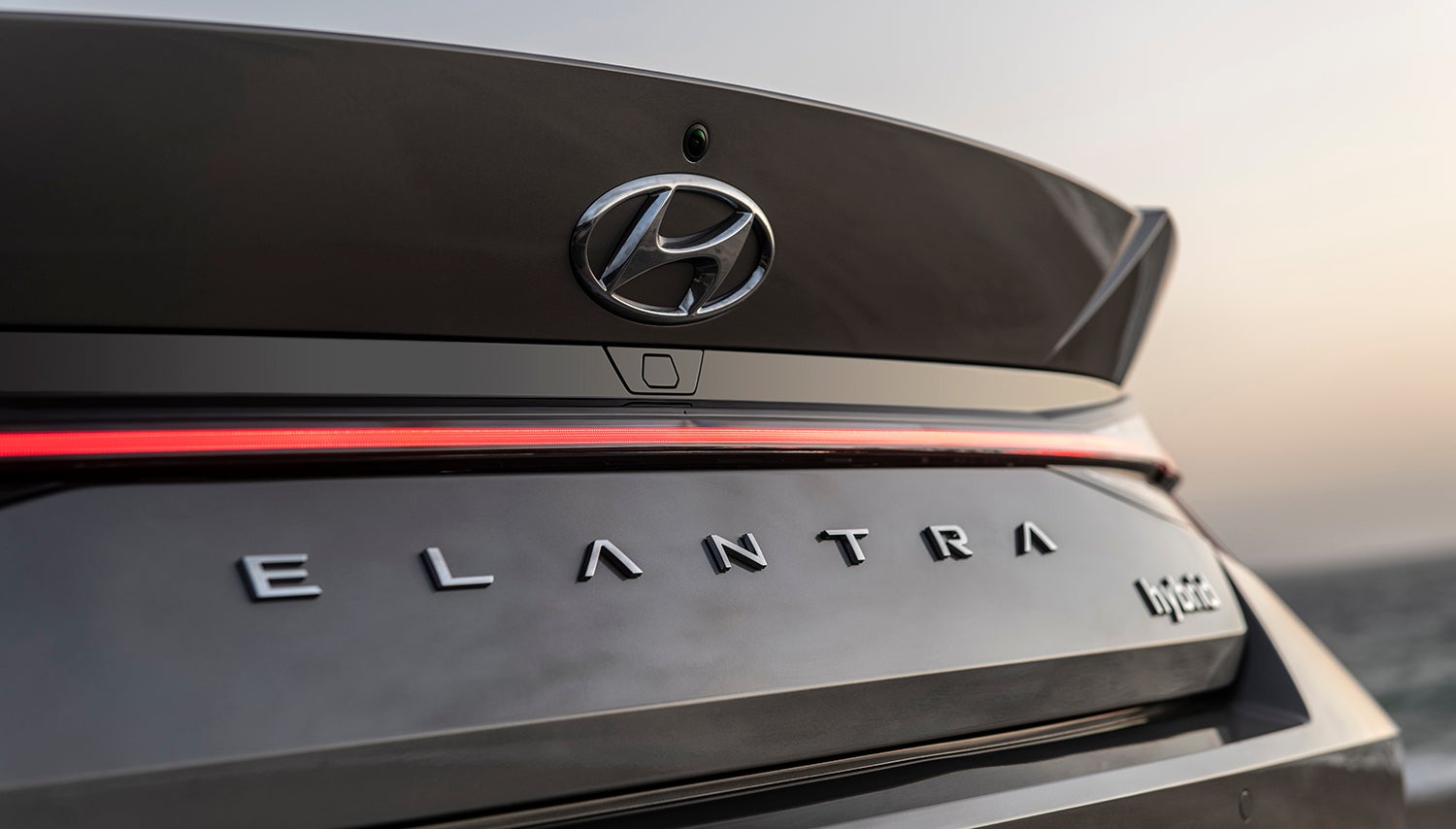 A close-up of the rear of a Hyundai Elantra Hybrid, showcasing the distinctive "ELANTRA Hybrid" lettering and the Hyundai logo.