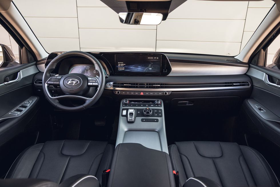 The interior of a Hyundai Palisade, showing the driver's seat, steering wheel, and dashboard with a large touchscreen display.