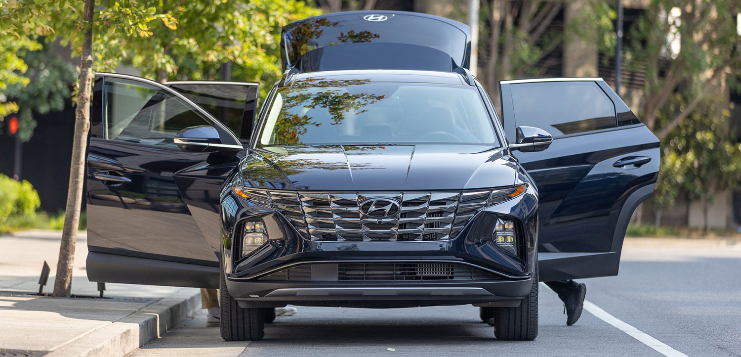 Dark blue Hyundai Tucson with doors and hatch open.