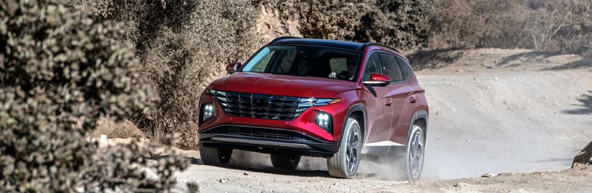 A red Hyundai Tucson driving confidently along a dirt road.