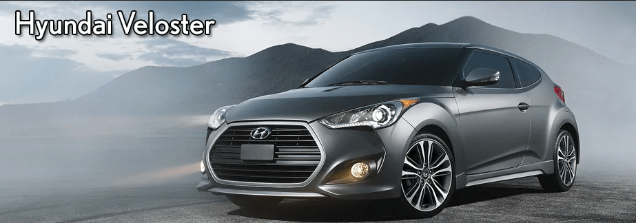 A gray Hyundai Veloster parked in a scenic location with mountains in the background.